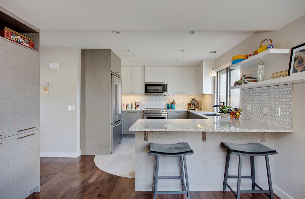 Example of a trendy u-shaped porcelain tile eat-in kitchen design in Calgary with an undermount sink, flat-panel cabinets, gray cabinets, granite countertops, gray backsplash, mosaic tile backsplash, stainless steel appliances and a peninsula