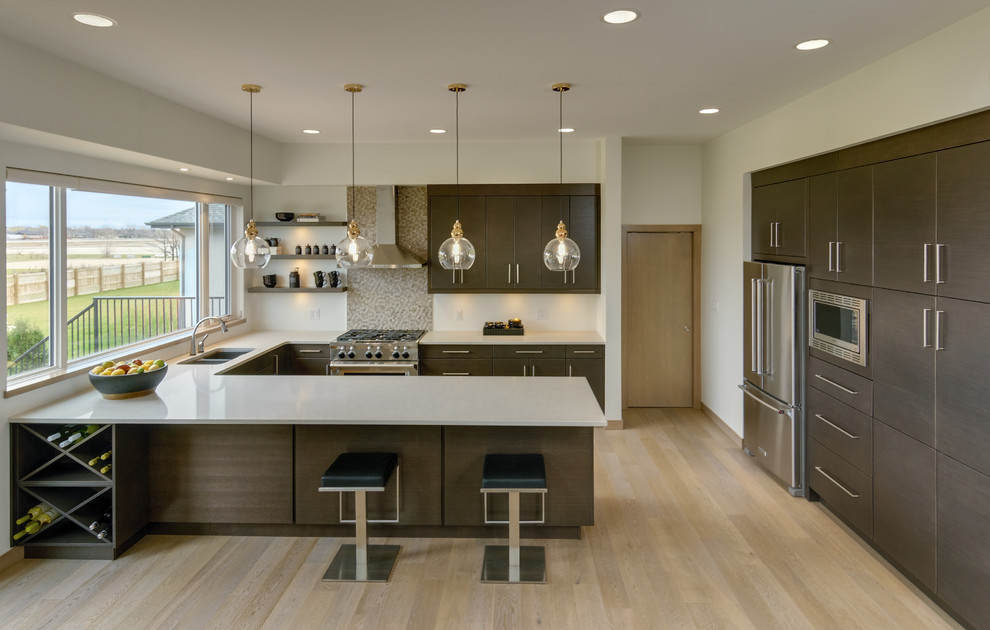 Modelo de cocinas en U contemporáneo, abierto, con armarios con paneles lisos, puertas de armario de madera oscura, encimera de cuarzo compacto, salpicadero multicolor, salpicadero con mosaicos de azulejos, electrodomésticos de acero inoxidable, suelo de madera clara y península