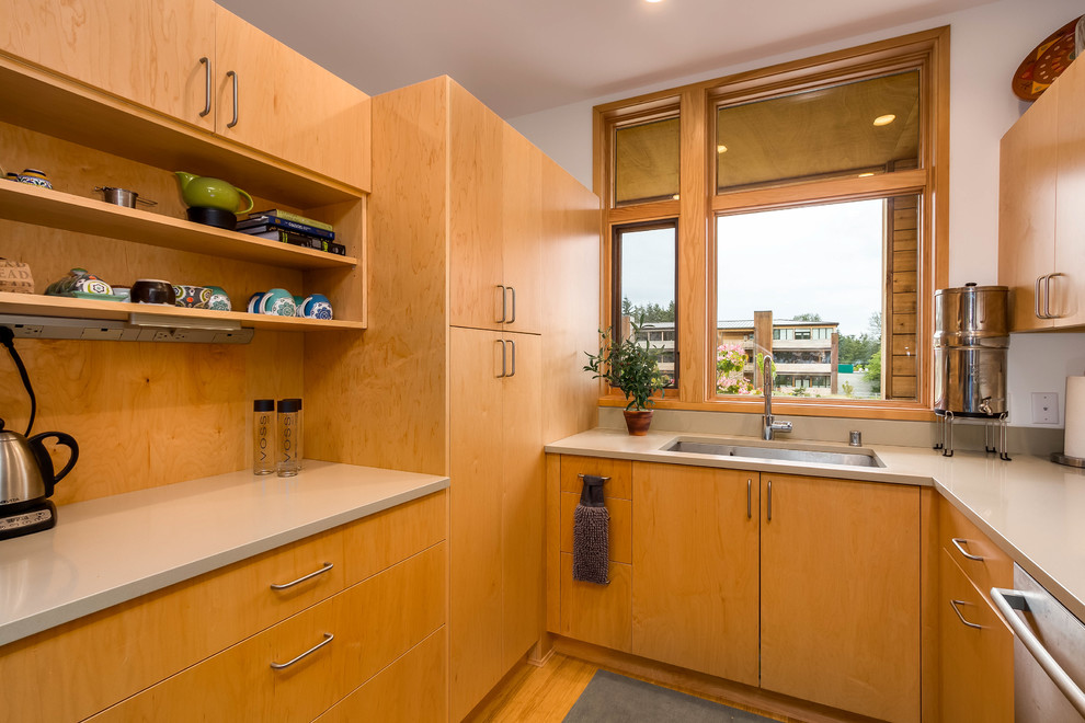 Bild på ett mellanstort funkis grå grått kök, med en undermonterad diskho, släta luckor, skåp i ljust trä, bänkskiva i kvartsit, grått stänkskydd, stänkskydd i sten, rostfria vitvaror och bambugolv