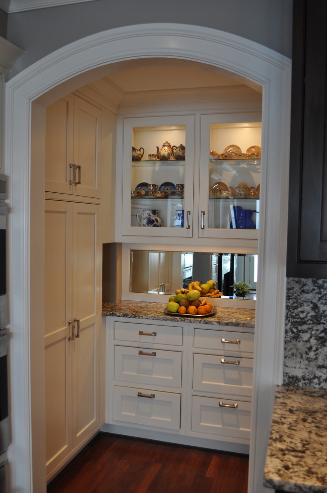Exempel på ett stort klassiskt kök, med luckor med profilerade fronter, vita skåp, granitbänkskiva, spegel som stänkskydd, rostfria vitvaror, en köksö, stänkskydd med metallisk yta och mörkt trägolv