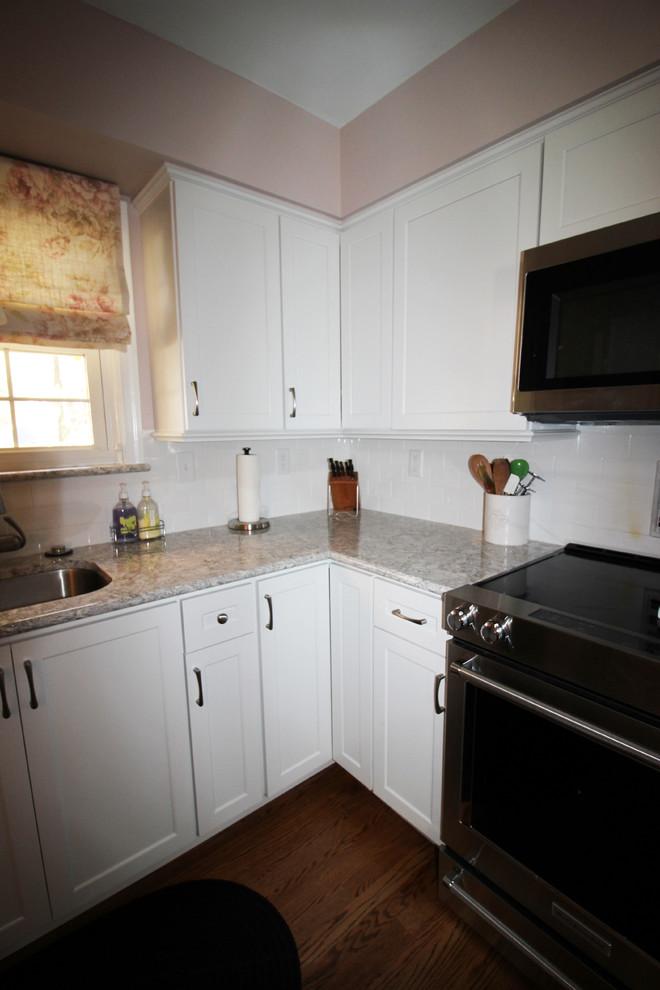 Exemple d'une cuisine chic de taille moyenne avec des portes de placard blanches, un plan de travail en quartz modifié, une crédence blanche, une crédence en carrelage métro et un électroménager en acier inoxydable.