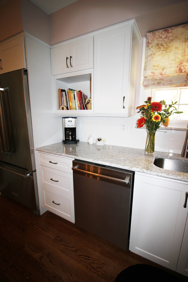 Diseño de cocina clásica renovada de tamaño medio con puertas de armario blancas, encimera de cuarzo compacto, salpicadero blanco, salpicadero de azulejos tipo metro y electrodomésticos de acero inoxidable