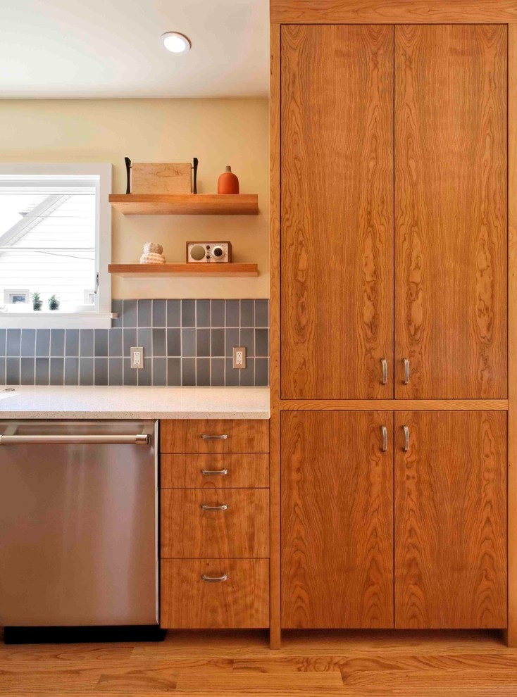 ポートランドにある高級なトランジショナルスタイルのおしゃれなキッチン (フラットパネル扉のキャビネット、中間色木目調キャビネット、再生ガラスカウンター、青いキッチンパネル、セラミックタイルのキッチンパネル、グレーとクリーム色) の写真