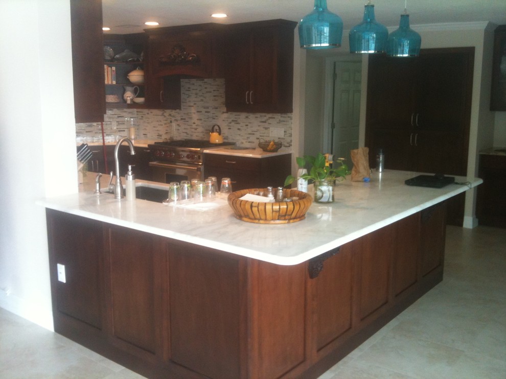 This is an example of a traditional kitchen/diner in Tampa with a submerged sink, shaker cabinets, dark wood cabinets, marble worktops, multi-coloured splashback, glass sheet splashback, stainless steel appliances and porcelain flooring.