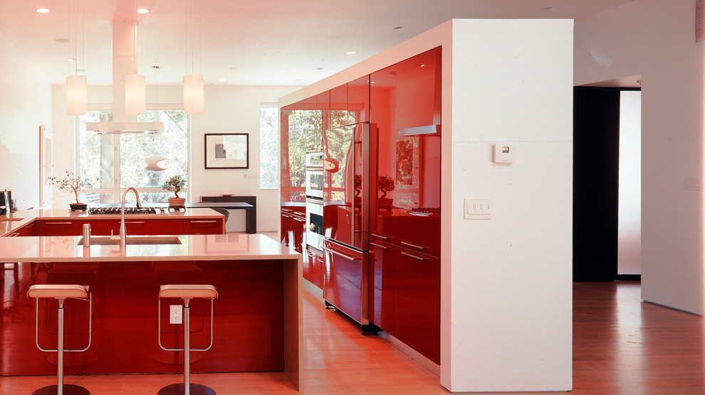 Eat-in kitchen - large contemporary u-shaped medium tone wood floor eat-in kitchen idea in DC Metro with an undermount sink, glass-front cabinets, red cabinets, quartz countertops, stainless steel appliances and an island
