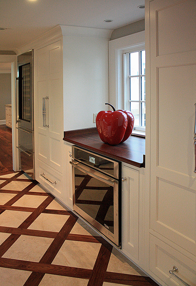 Example of a large classic galley kitchen pantry design in New York with beaded inset cabinets, white cabinets, granite countertops, white backsplash, ceramic backsplash and an island