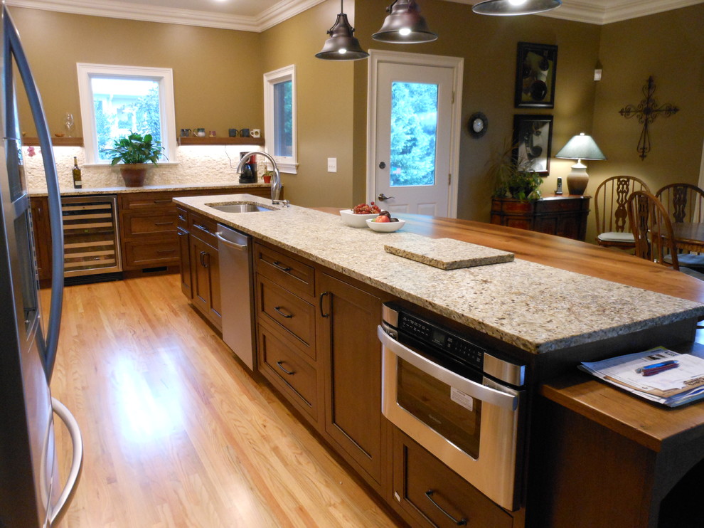 Example of a classic l-shaped light wood floor eat-in kitchen design in Birmingham with a single-bowl sink, shaker cabinets, medium tone wood cabinets, granite countertops, beige backsplash, stone tile backsplash, stainless steel appliances and an island