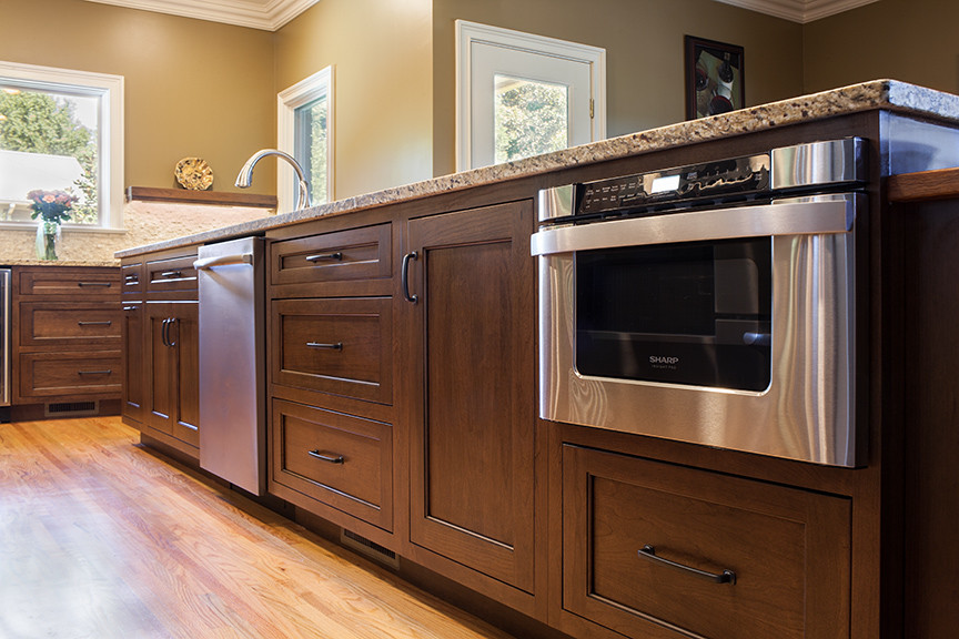 Eat-in kitchen - mid-sized traditional l-shaped light wood floor eat-in kitchen idea in Birmingham with an undermount sink, shaker cabinets, medium tone wood cabinets, granite countertops, beige backsplash, stainless steel appliances and an island