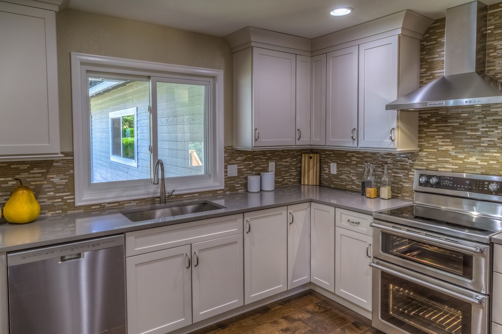 Mid-sized trendy u-shaped dark wood floor and brown floor eat-in kitchen photo in Portland with an undermount sink, shaker cabinets, white cabinets, laminate countertops, brown backsplash, mosaic tile backsplash, stainless steel appliances and a peninsula