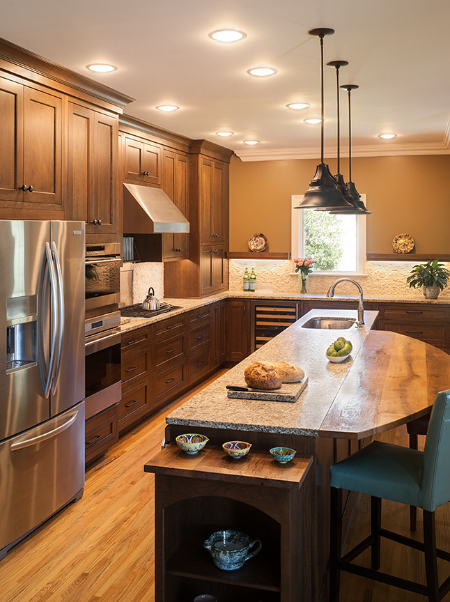 Inspiration for a mid-sized transitional l-shaped light wood floor open concept kitchen remodel in Birmingham with a single-bowl sink, beaded inset cabinets, medium tone wood cabinets, granite countertops, white backsplash, stone tile backsplash, stainless steel appliances and an island