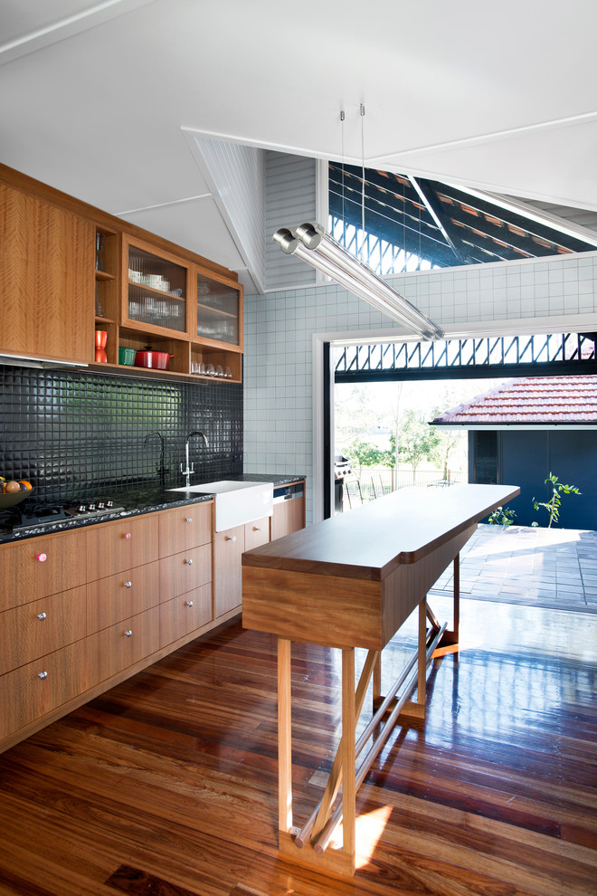 Foto di una cucina minimal con lavello stile country, ante lisce, ante in legno scuro, paraspruzzi nero e pavimento in legno massello medio