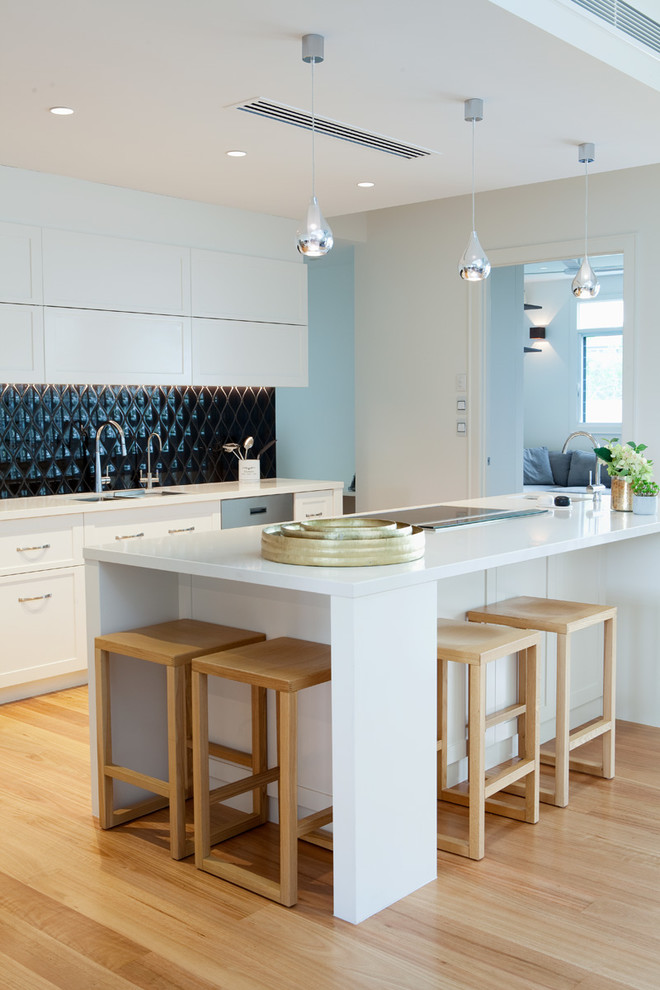 Esempio di un cucina con isola centrale minimalista di medie dimensioni con paraspruzzi nero e elettrodomestici in acciaio inossidabile