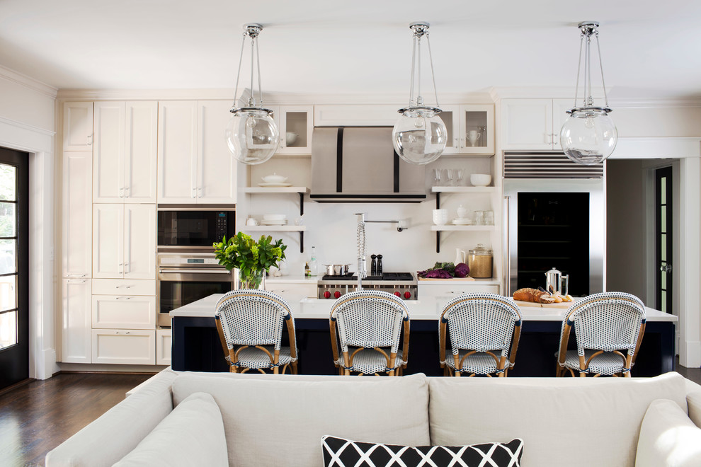 Open concept kitchen - transitional galley dark wood floor open concept kitchen idea in Atlanta with a farmhouse sink, recessed-panel cabinets, solid surface countertops, white backsplash, stainless steel appliances and an island