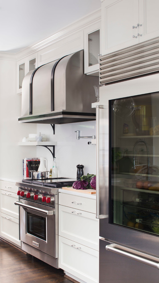 Klassisk inredning av ett mellanstort linjärt kök med öppen planlösning, med en rustik diskho, luckor med infälld panel, vita skåp, bänkskiva i koppar, vitt stänkskydd, rostfria vitvaror, mörkt trägolv och en köksö