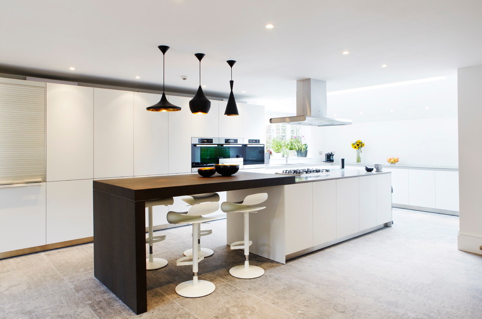 Foto på ett stort funkis kök och matrum, med släta luckor, vita skåp, bänkskiva i kvarts, rostfria vitvaror, kalkstensgolv, en köksö och grått golv