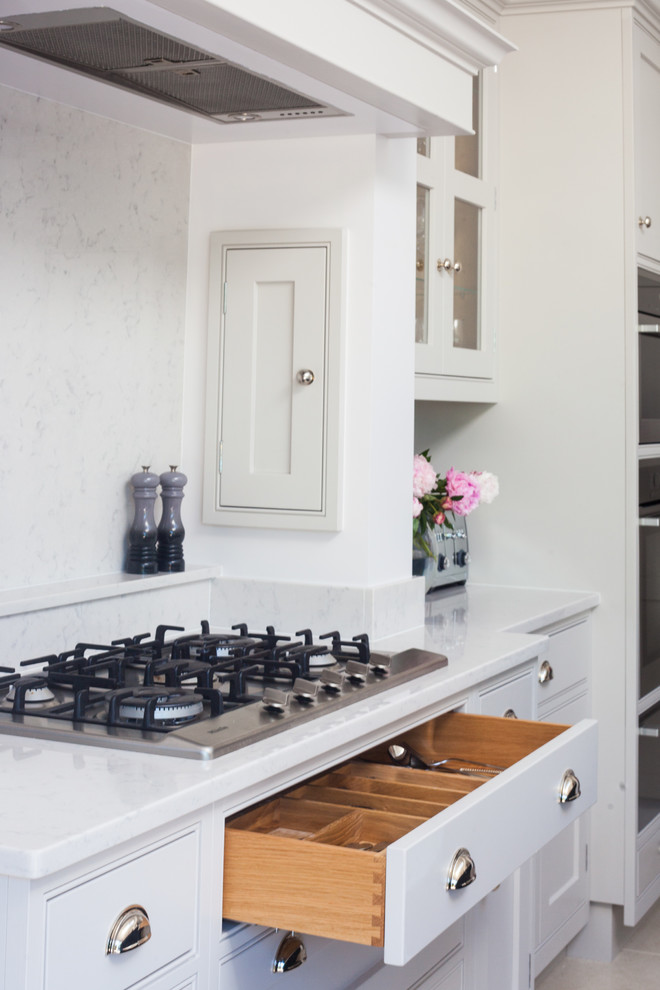 Cette photo montre une grande cuisine chic avec des portes de placard grises, un plan de travail en quartz et îlot.