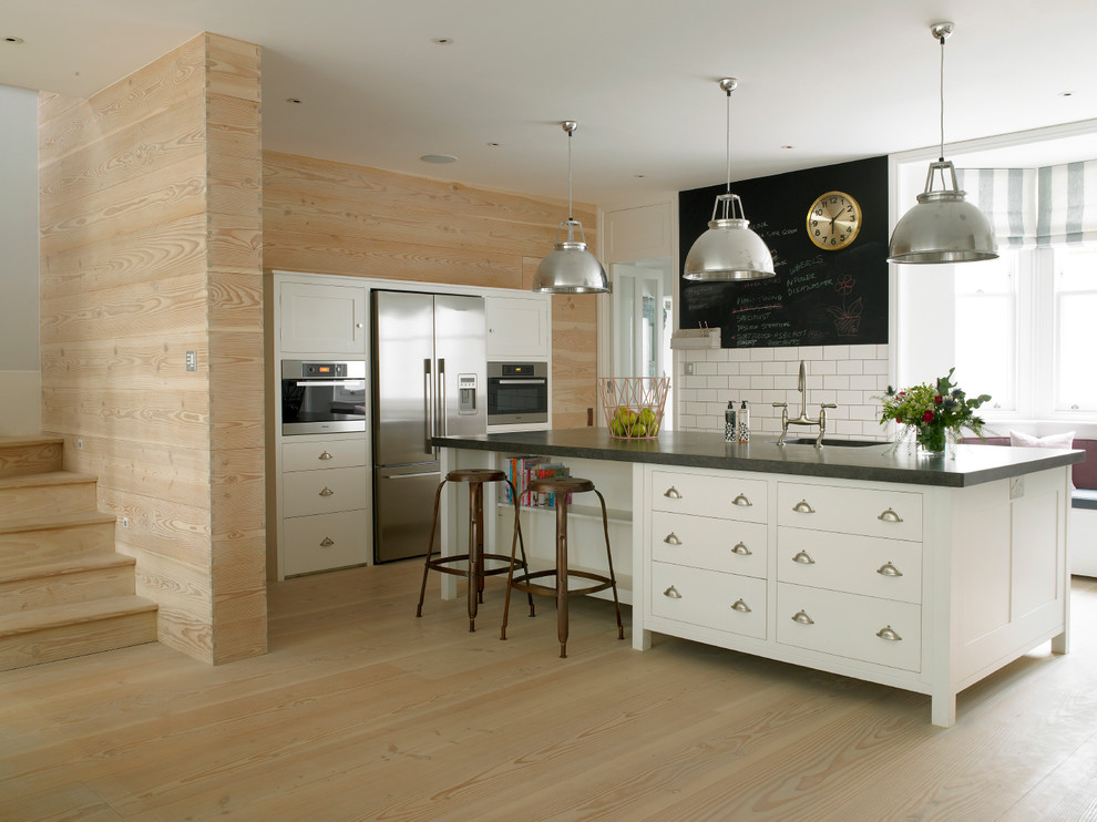 Exempel på ett mellanstort klassiskt grå grått kök, med vita skåp, rostfria vitvaror, en nedsänkt diskho, skåp i shakerstil, bänkskiva i kalksten, vitt stänkskydd, stänkskydd i tunnelbanekakel, ljust trägolv, en köksö och beiget golv