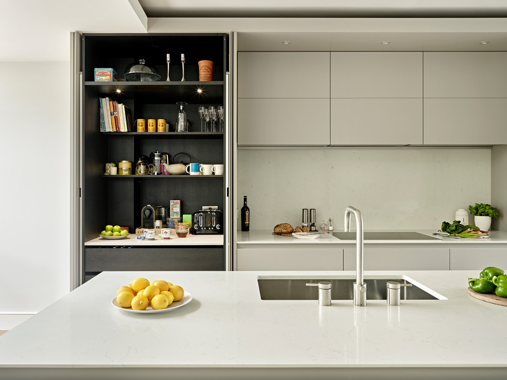 Inredning av ett modernt kök med öppen planlösning, med släta luckor, grå skåp, bänkskiva i koppar, grått stänkskydd, ljust trägolv, en köksö, brunt golv och en undermonterad diskho
