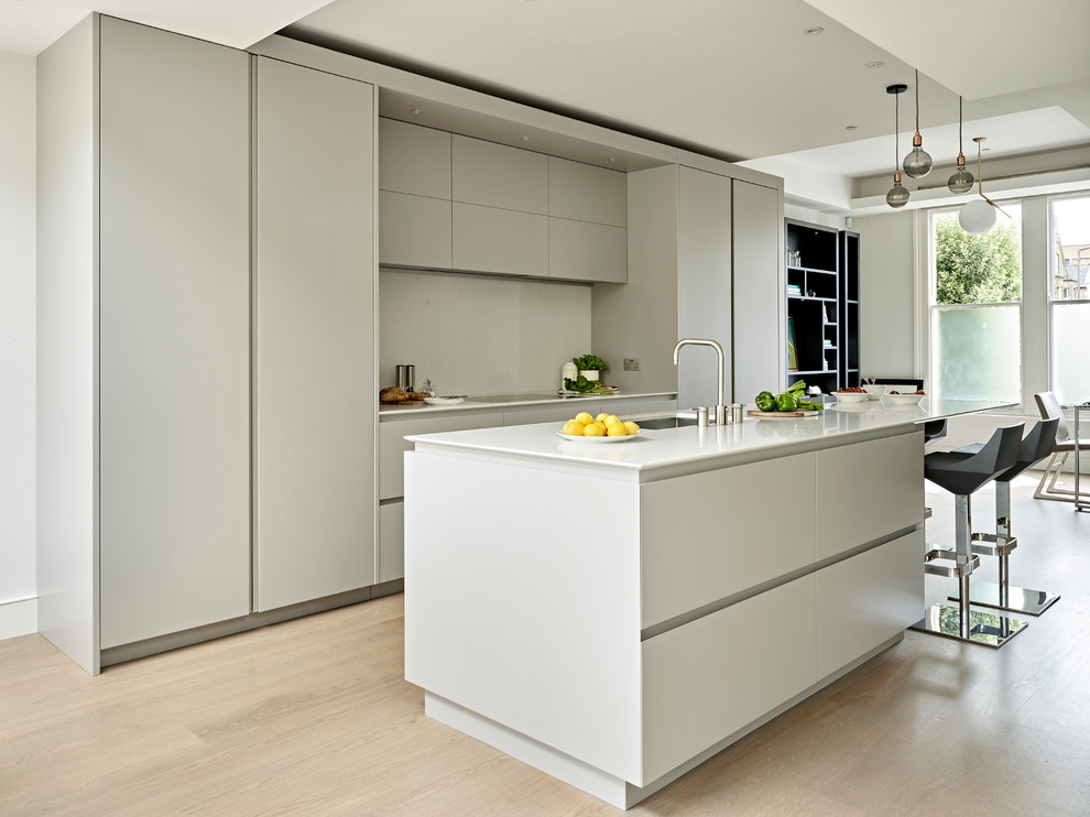 Foto de cocina moderna abierta con armarios con paneles lisos, puertas de armario grises, encimera de acrílico, suelo de madera clara, una isla y suelo marrón