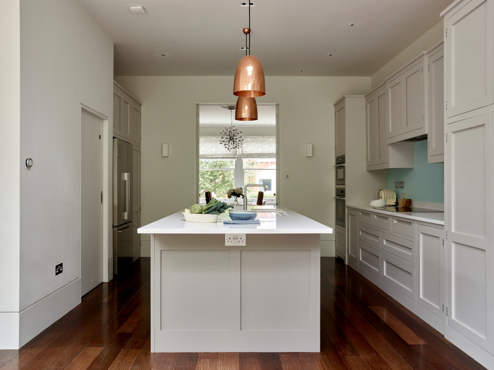 Idéer för ett mellanstort modernt vit kök och matrum, med en integrerad diskho, skåp i shakerstil, grå skåp, bänkskiva i kvartsit, blått stänkskydd, glaspanel som stänkskydd, rostfria vitvaror, mörkt trägolv, en köksö och brunt golv