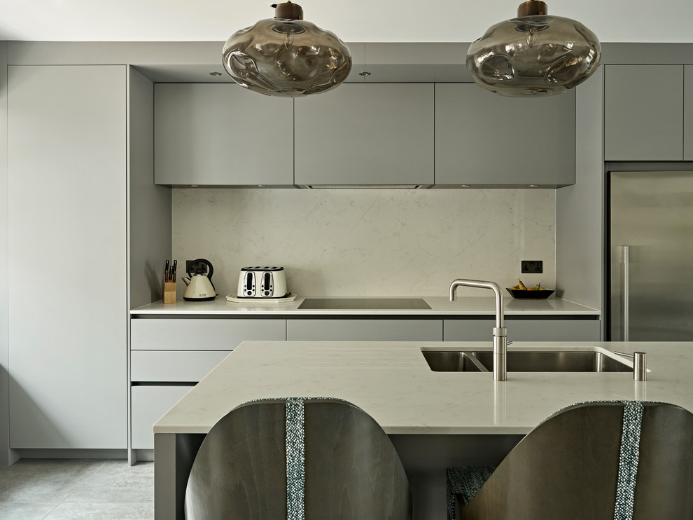 Cette image montre une cuisine linéaire design fermée et de taille moyenne avec un placard à porte plane, des portes de placard grises et îlot.