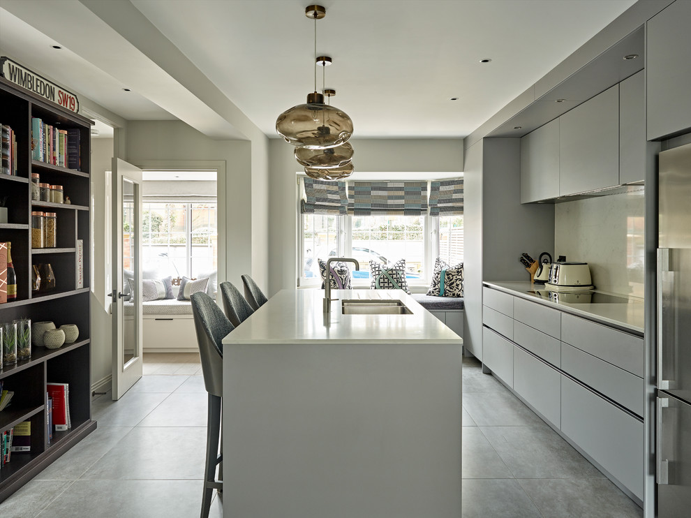 Inspiration for a medium sized contemporary single-wall enclosed kitchen in London with a double-bowl sink, flat-panel cabinets, grey cabinets, white splashback, stainless steel appliances, an island, grey floors and white worktops.