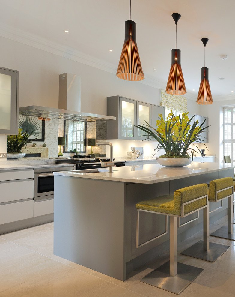 Large contemporary galley open plan kitchen in London with a submerged sink, glass-front cabinets, grey cabinets, stainless steel appliances, an island and grey floors.