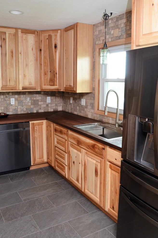 Foto på ett avskilt, mellanstort rustikt brun l-kök, med en nedsänkt diskho, luckor med upphöjd panel, skåp i ljust trä, träbänkskiva, brunt stänkskydd, stänkskydd i keramik, rostfria vitvaror, grått golv och cementgolv