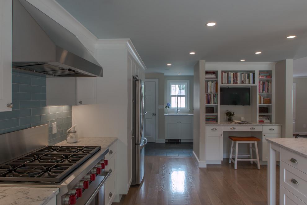 Kitchen - traditional u-shaped medium tone wood floor kitchen idea in Boston with a farmhouse sink, recessed-panel cabinets, white cabinets, quartz countertops, blue backsplash, glass tile backsplash, stainless steel appliances and an island