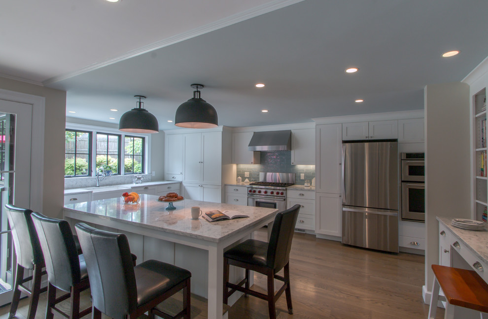 Kitchen - traditional u-shaped medium tone wood floor kitchen idea in Boston with a farmhouse sink, recessed-panel cabinets, white cabinets, quartz countertops, blue backsplash, glass tile backsplash, stainless steel appliances and an island