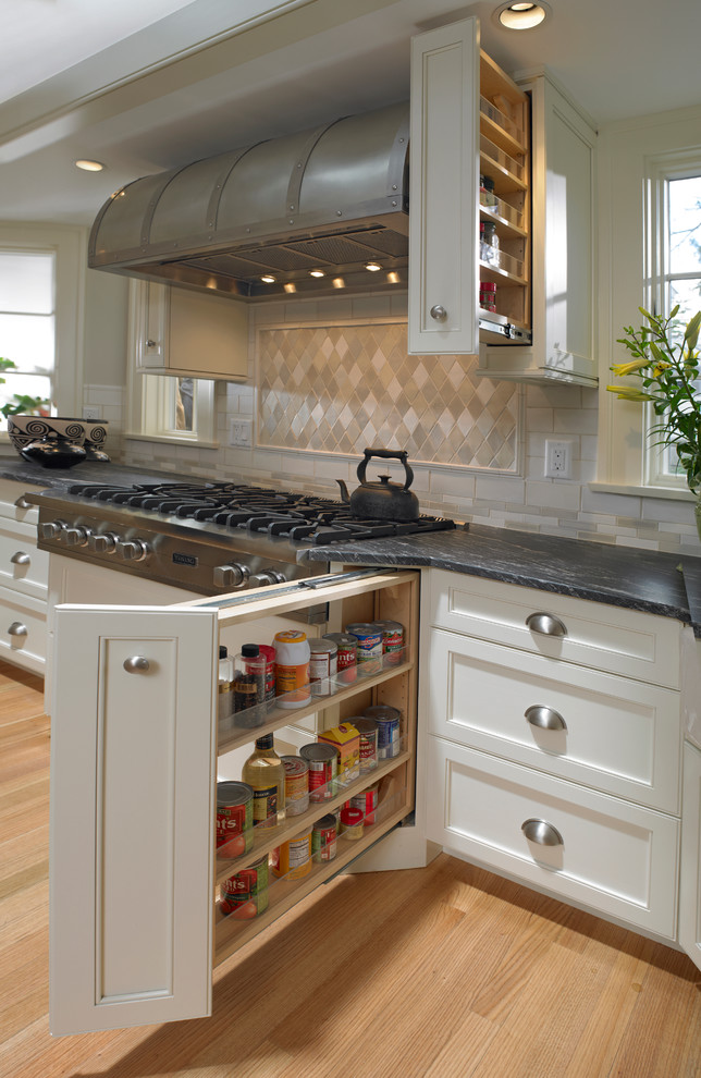 Exempel på ett stort lantligt kök, med en rustik diskho, luckor med infälld panel, vita skåp, beige stänkskydd, stänkskydd i tunnelbanekakel, rostfria vitvaror, ljust trägolv och en köksö