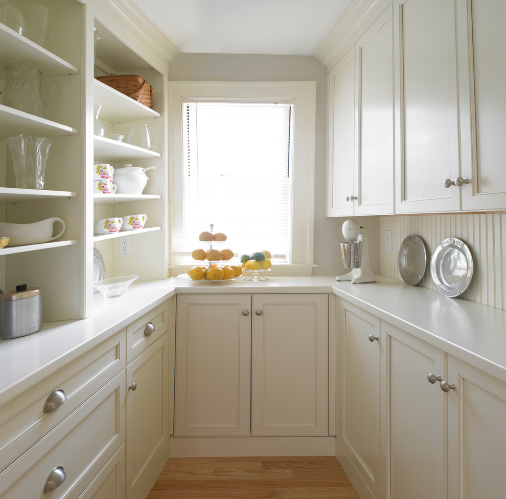 Inspiration for a large timeless u-shaped medium tone wood floor kitchen pantry remodel in Boston with recessed-panel cabinets, white cabinets, solid surface countertops, white backsplash, wood backsplash and no island