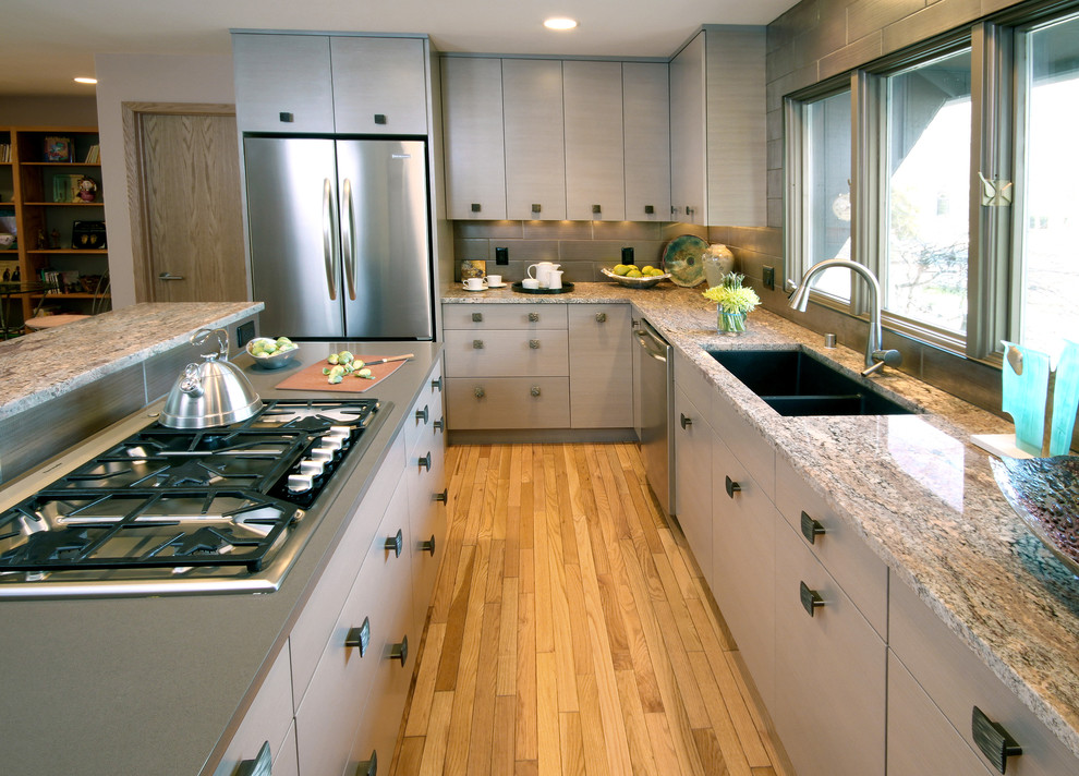 Diseño de cocina actual con electrodomésticos de acero inoxidable, encimera de esteatita, armarios con paneles lisos, puertas de armario grises y salpicadero verde