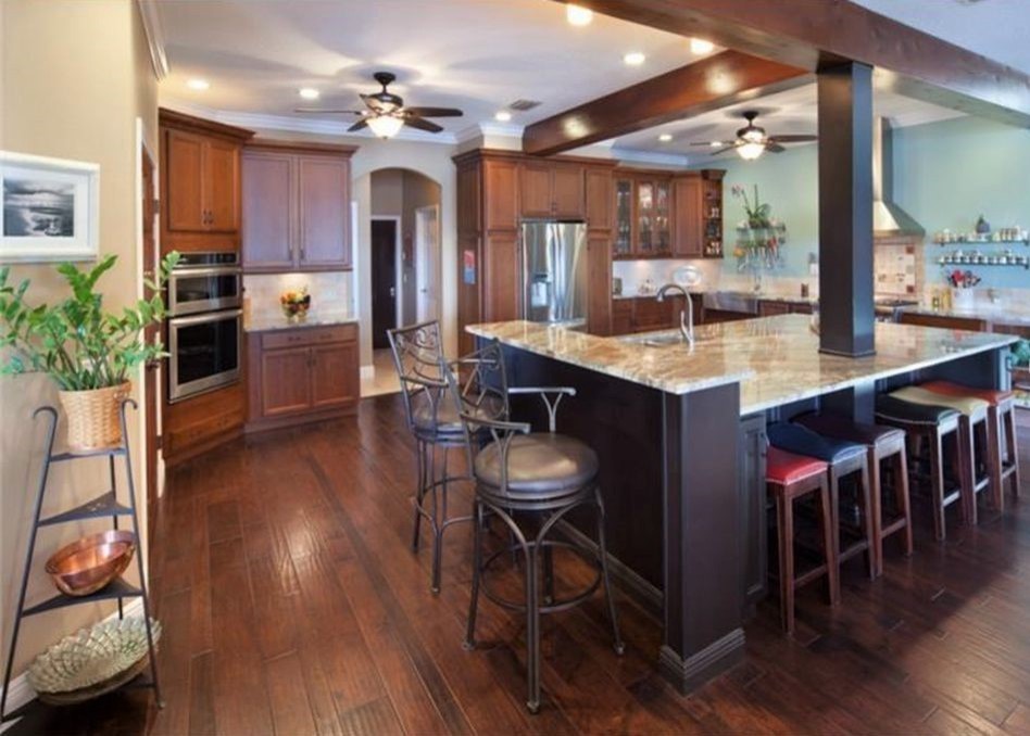 Photo of a large traditional u-shaped kitchen in Orlando with a belfast sink, flat-panel cabinets, dark wood cabinets, granite worktops, stainless steel appliances, dark hardwood flooring, an island and brown floors.
