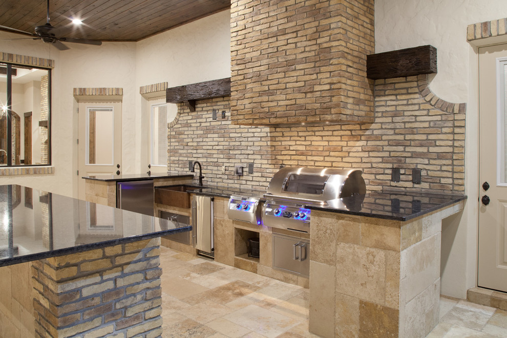 Example of a large tuscan single-wall travertine floor eat-in kitchen design in Orlando with a farmhouse sink, granite countertops, beige backsplash, subway tile backsplash, stainless steel appliances, an island, flat-panel cabinets and stainless steel cabinets