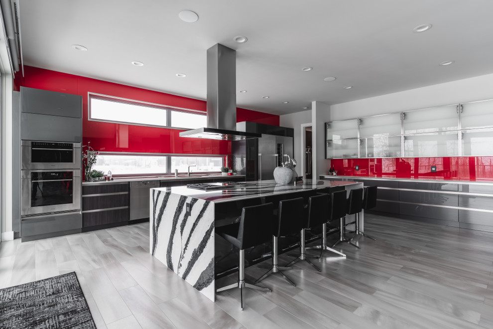 Inspiration för moderna flerfärgat l-kök, med släta luckor, grå skåp, rött stänkskydd, glaspanel som stänkskydd, rostfria vitvaror, en köksö och grått golv