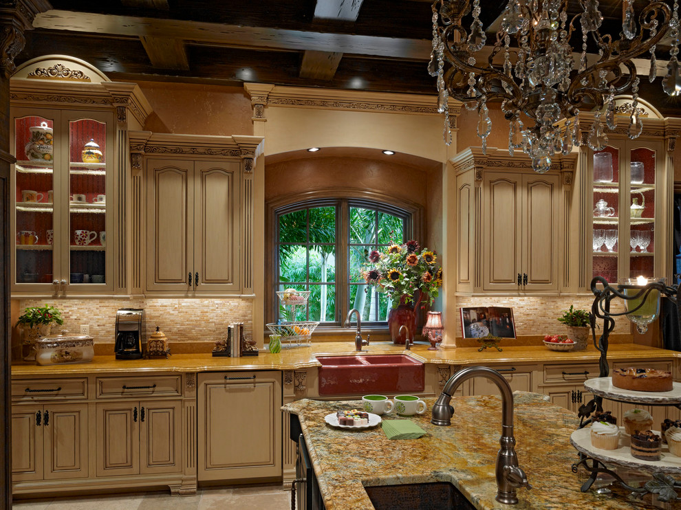 This is an example of a large mediterranean u-shaped enclosed kitchen in Orlando with a belfast sink, raised-panel cabinets, beige cabinets, granite worktops, beige splashback, stone tiled splashback, integrated appliances, travertine flooring and multiple islands.