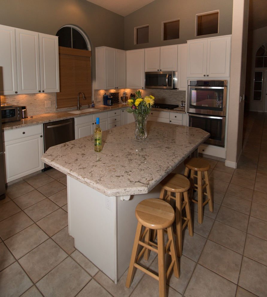 Example of a mid-sized classic u-shaped open concept kitchen design in Other with an undermount sink, white cabinets, quartz countertops, beige backsplash, stone tile backsplash, stainless steel appliances and an island