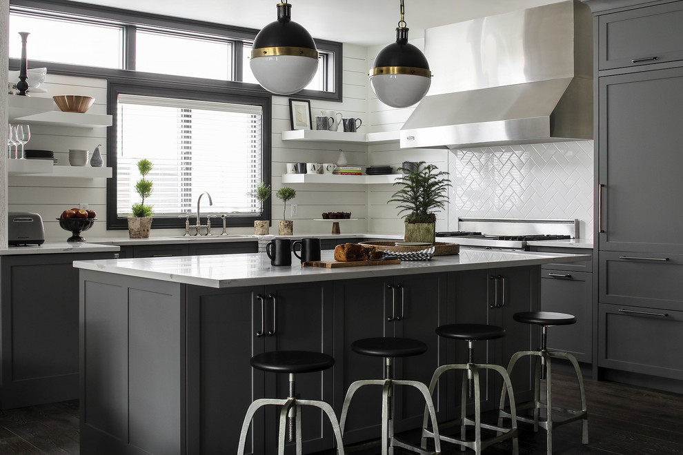 Rustic l-shaped kitchen in New York with shaker cabinets, grey cabinets, white splashback, ceramic splashback, dark hardwood flooring, an island and brown floors.