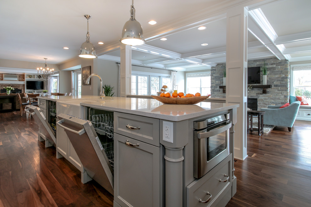 Large traditional kitchen in Chicago with a belfast sink, recessed-panel cabinets, white cabinets, quartz worktops, stainless steel appliances, dark hardwood flooring, an island, brown floors and white worktops.