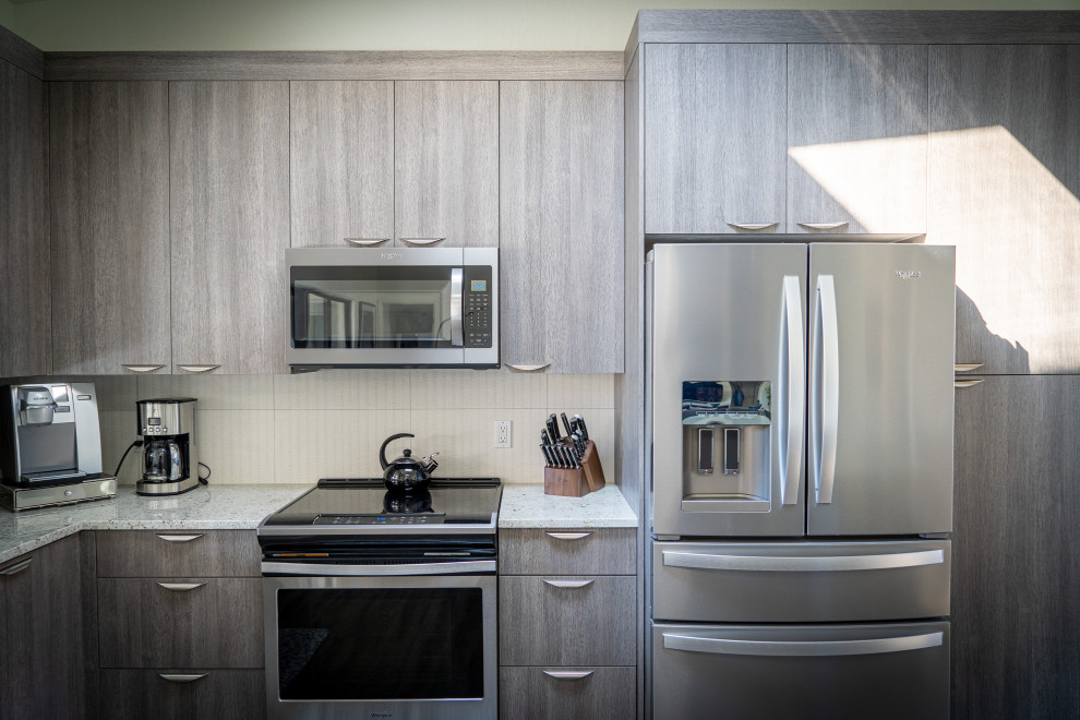 Aménagement d'une cuisine contemporaine avec un placard à porte plane, des portes de placard grises, un électroménager en acier inoxydable et îlot.