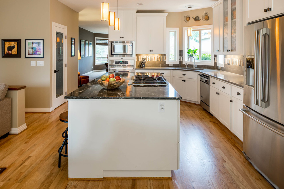 Modern inredning av ett mellanstort kök, med en undermonterad diskho, skåp i shakerstil, vita skåp, bänkskiva i kvarts, grått stänkskydd, stänkskydd i porslinskakel, rostfria vitvaror, ljust trägolv och en köksö