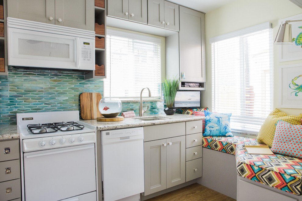 Inspiration for a small beach style single-wall open plan kitchen in San Diego with a submerged sink, grey cabinets, green splashback, white appliances, no island, shaker cabinets, granite worktops, glass sheet splashback, vinyl flooring and brown floors.