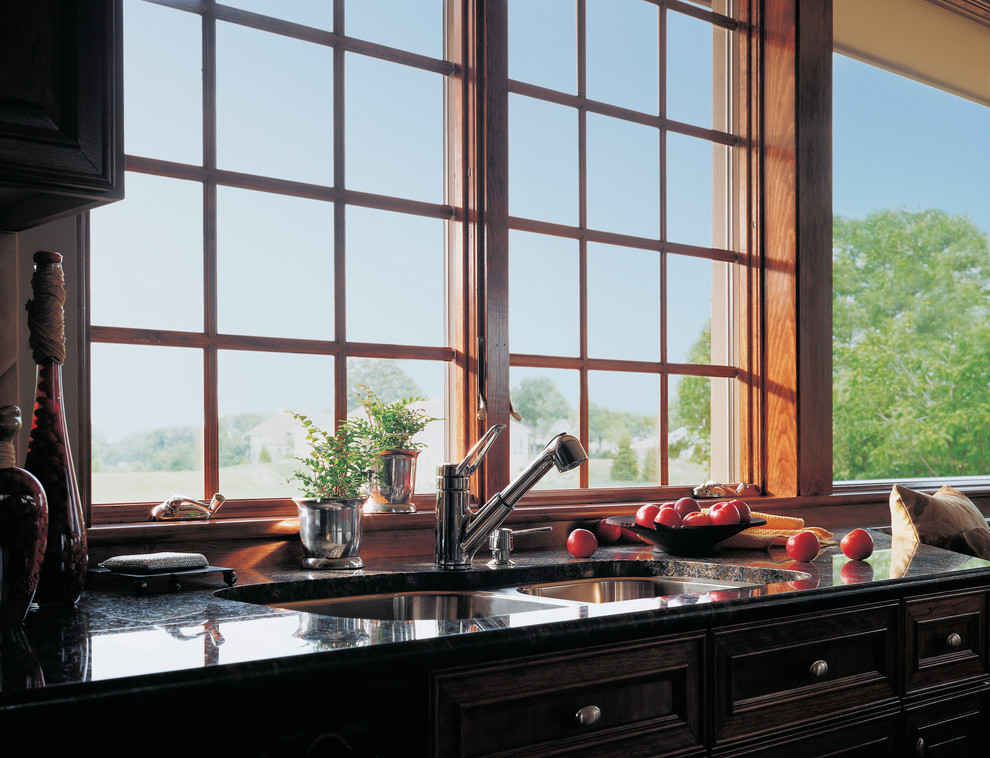 Exemple d'une cuisine américaine chic en L et bois foncé de taille moyenne avec un plan de travail en granite et un électroménager noir.