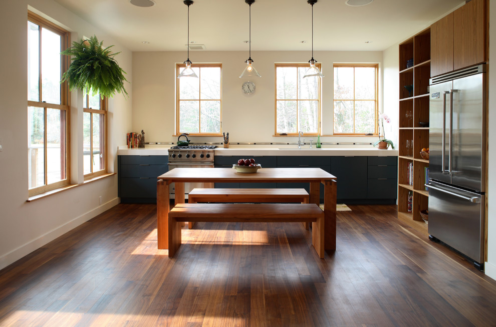 Aménagement d'une cuisine classique en L et bois brun avec un évier encastré, un placard à porte plane, un électroménager en acier inoxydable, un sol en bois brun et fenêtre au-dessus de l'évier.