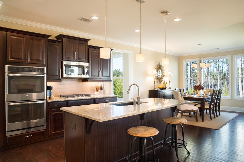 Example of a mid-sized eclectic l-shaped dark wood floor eat-in kitchen design in Atlanta with an undermount sink, raised-panel cabinets, dark wood cabinets, granite countertops, beige backsplash, ceramic backsplash, stainless steel appliances and an island