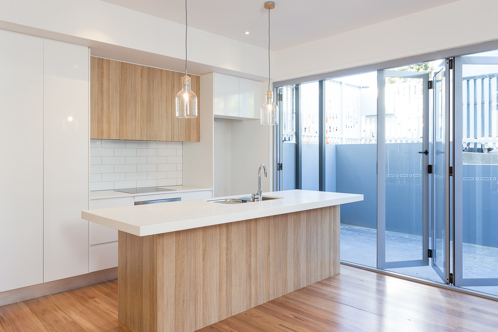 Inspiration for a modern galley medium tone wood floor eat-in kitchen remodel in Brisbane with an undermount sink, open cabinets, light wood cabinets, glass countertops, white backsplash, ceramic backsplash, stainless steel appliances and an island