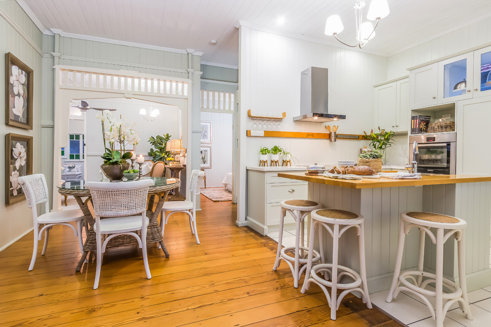 Country Wohnküche in L-Form mit Schrankfronten im Shaker-Stil, grauen Schränken, Arbeitsplatte aus Holz, Küchengeräten aus Edelstahl, braunem Holzboden, Kücheninsel und braunem Boden in Brisbane