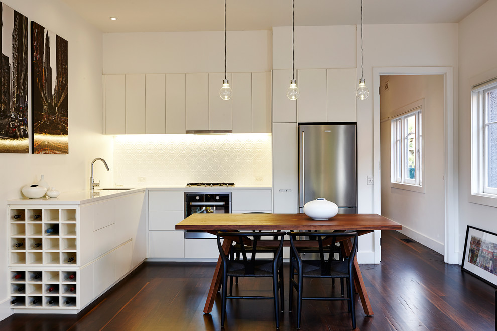 Foto på ett funkis kök, med en undermonterad diskho, släta luckor, vita skåp, bänkskiva i kvartsit, vitt stänkskydd, stänkskydd i metallkakel, rostfria vitvaror och mörkt trägolv