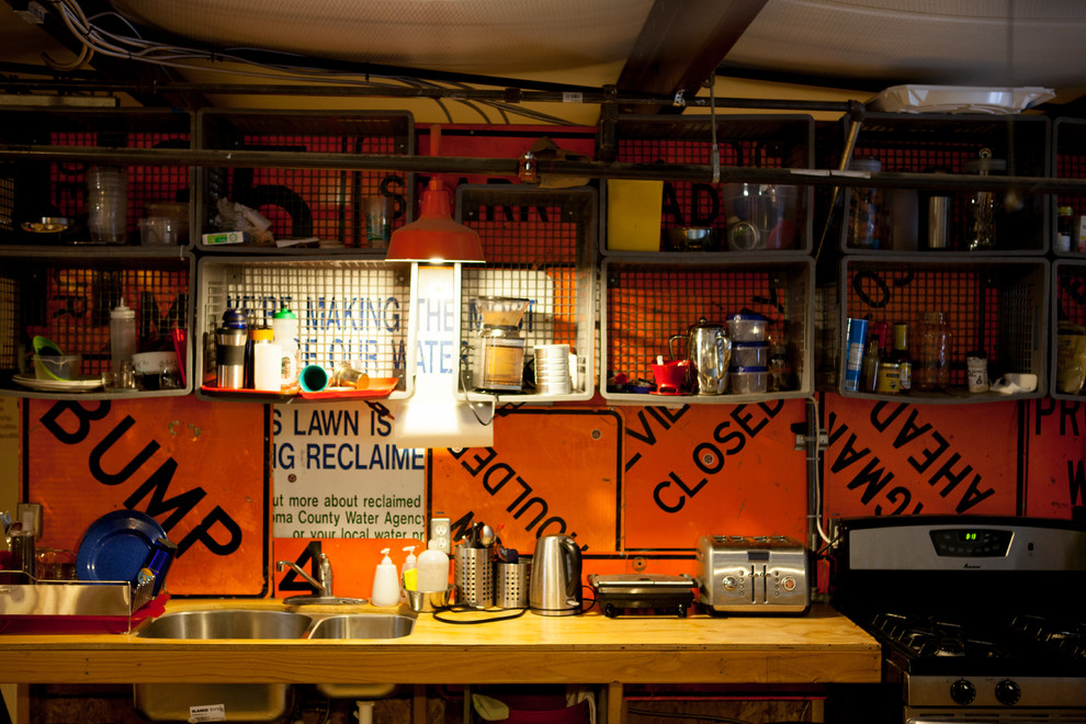 Inspiration for a small industrial galley kitchen/diner in San Francisco with a submerged sink, open cabinets, light wood cabinets, wood worktops, orange splashback, metal splashback, stainless steel appliances, plywood flooring and no island.